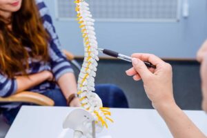 A chiropractor performing a spinal adjustment on a patient lying face down on an exam table.