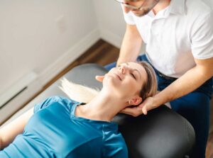A person gently massaging a tight spot on their upper back with a tennis ball against a wall.