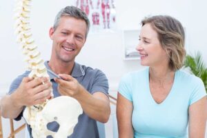 Patient discusses spinal manipulation risks with a chiropractor in a bright clinical examination room.
