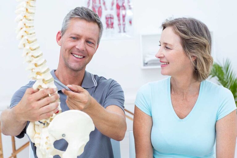 Patient discusses spinal manipulation risks with a chiropractor in a bright clinical examination room.